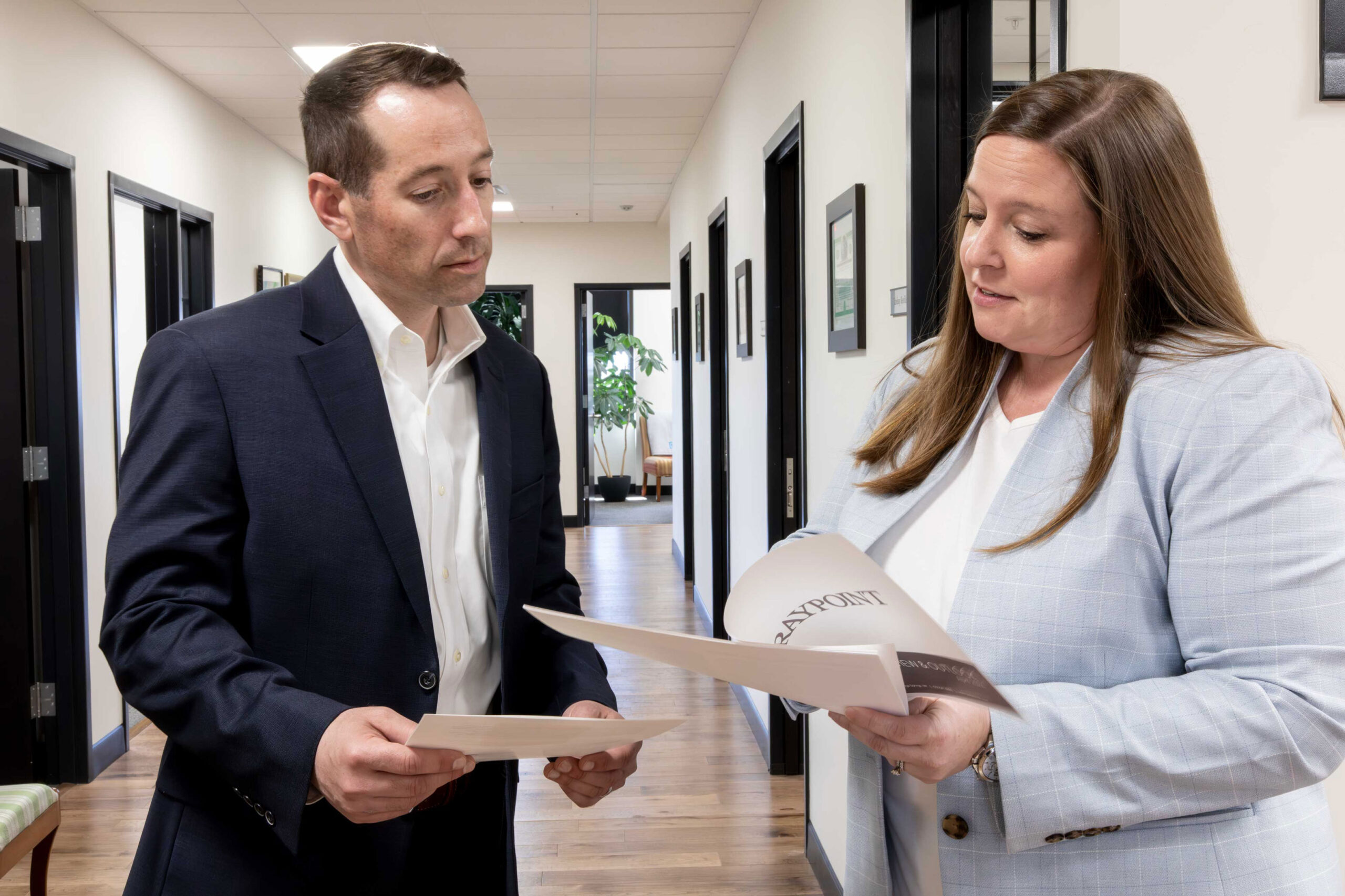 Two graypoint advisors meet in the hallway to review a document together